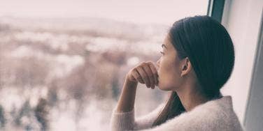 woman looking out window at cityscape