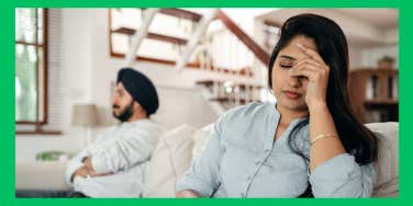 upset wife sitting beside husband on couch
