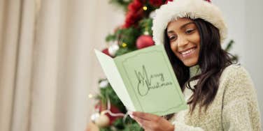 woman smiling while reading Christmas card