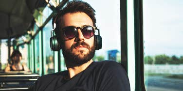 handsome man in sunglasses and headphones on bus