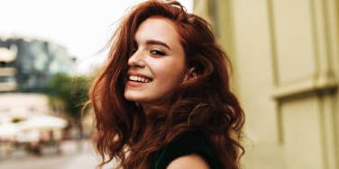 redhead woman looks over shoulder, smiling