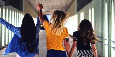 group of three teenaged girls walking down hallway together
