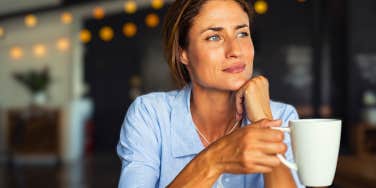 thoughtful woman holding coffee mug looking upward