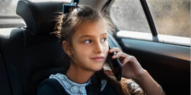 young teen rides in the backseat of an uber while on the phone 