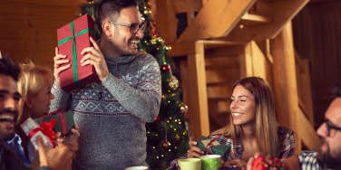 friends sitting next to a nicely decorated Christmas tree and exchanging Christmas presents and having fun