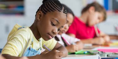 close up shot of students writing at their desk in school