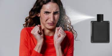 woman in red sweater grimacing in spray of perfume