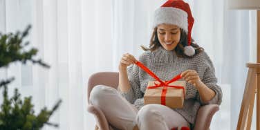 woman wearing santa hat opening christmas gift