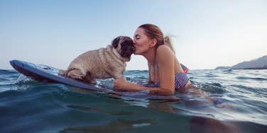 woman surfing with her dog