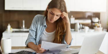 woman looking at sheet of paper in her hands with serious and focused expression on her face