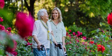 elderly woman and young woman walking around garden