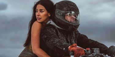 confident woman riding on the back of her boyfriend's motorcycle