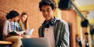 Young boy sitting with his laptop at school