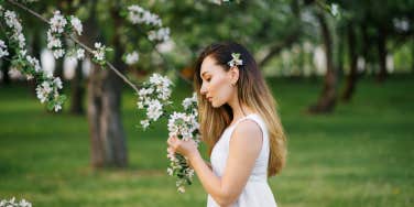 woman smelling flowers on tree