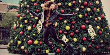 girl jumping in front of christmas tree