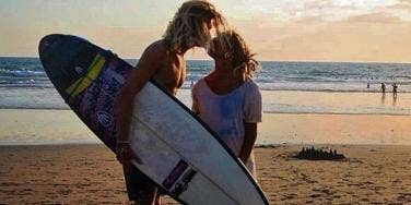 surfer couple kiss at the beach surfer couple kiss at the beach