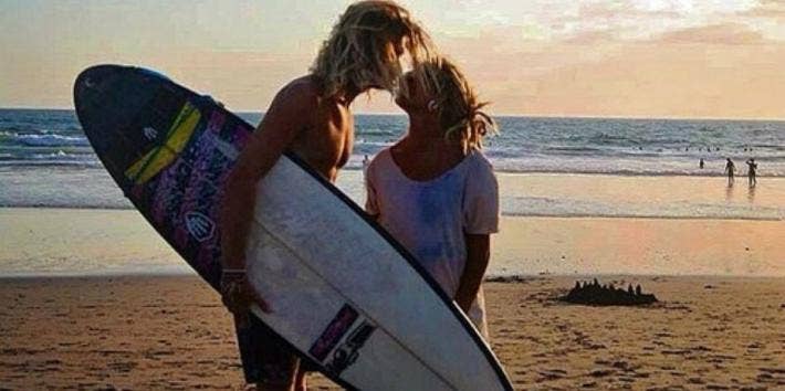 surfer couple kiss at the beach