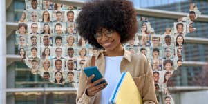 Happy Black girl scroll dating app on cell phone device on university campus background.