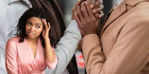 woman with a shocked expression as her friend and his partner grasp each others hands in anticipation