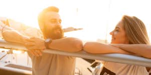 man and woman hanging out over boat rail-touching elbows