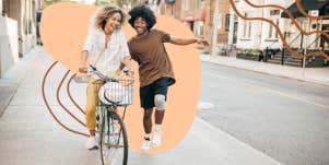 Woman riding a bike while man behind her cheers