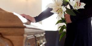 man holding flowers near casket 