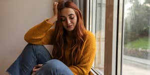 girl sitting alone at home near window