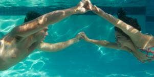 couple holding hands under water
