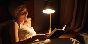 woman reading book in bed at night