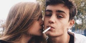Guy smoking, girl kissing him