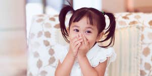 child covering her mouth