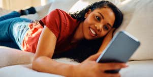 woman laying on couch texting