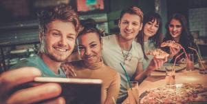 friends eating pizza together taking selfie
