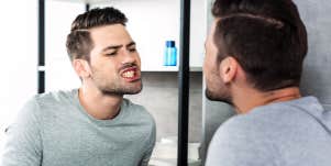 man checking teeth in mirror