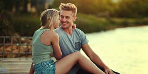 man and woman cuddling by lake