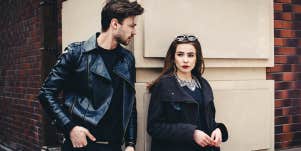 man and woman standing outside wearing leather jackets