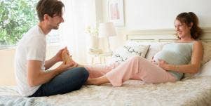 man rubbing woman's feet