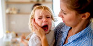toddler crying in mother's arms