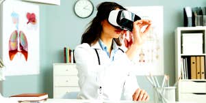 Physician sitting at her desk wearing VR mask to diagnose patient