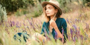 woman in hat sits calmly in lavender field 