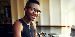 woman sitting at a table with laptop, smiling at camera