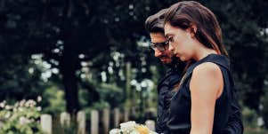 couple looking sadly at a grave