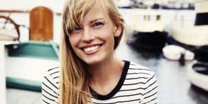 Blonde woman smiling in front of boats