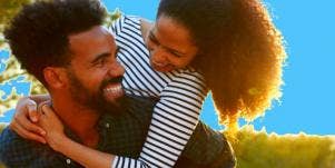 attractive Black couple snuggles playfully in front of a vibrant blue background