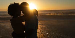 silhouette of couple hugging at sunset on the beach