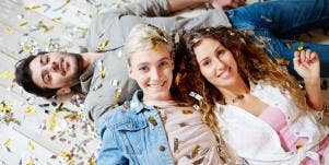 two women and one man lying on the floor with confetti