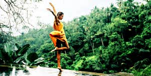 Woman in yellow dress dances in front of a jungle