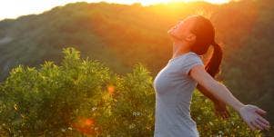 woman holding out arms in sunshine