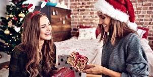 best friends exchanging gifts in front of a christmas tree