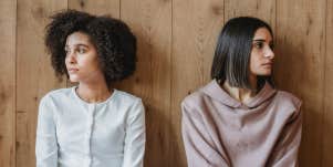 pensive women near wooden wall looking away from each other
